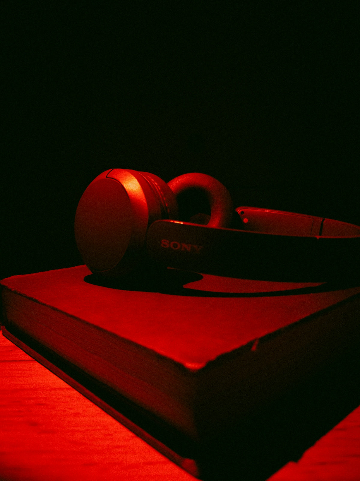 Red headphones rest on a closed book.