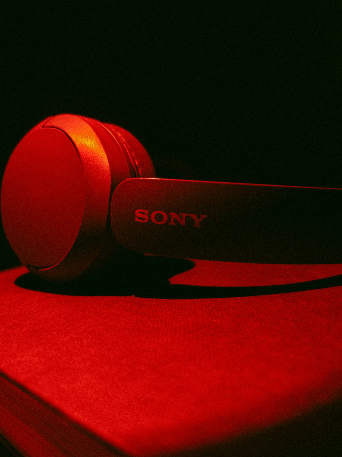 Red sony headphones resting on a dark surface.
