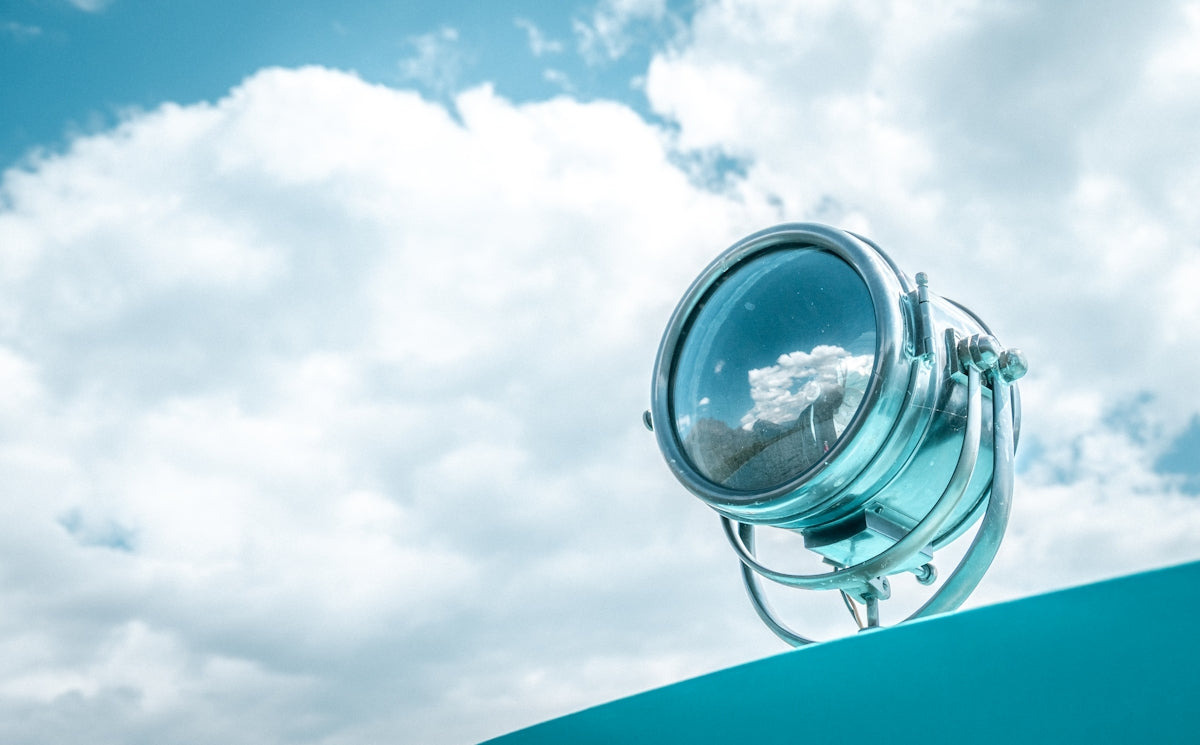 Spotlight reflecting clouds against a blue sky