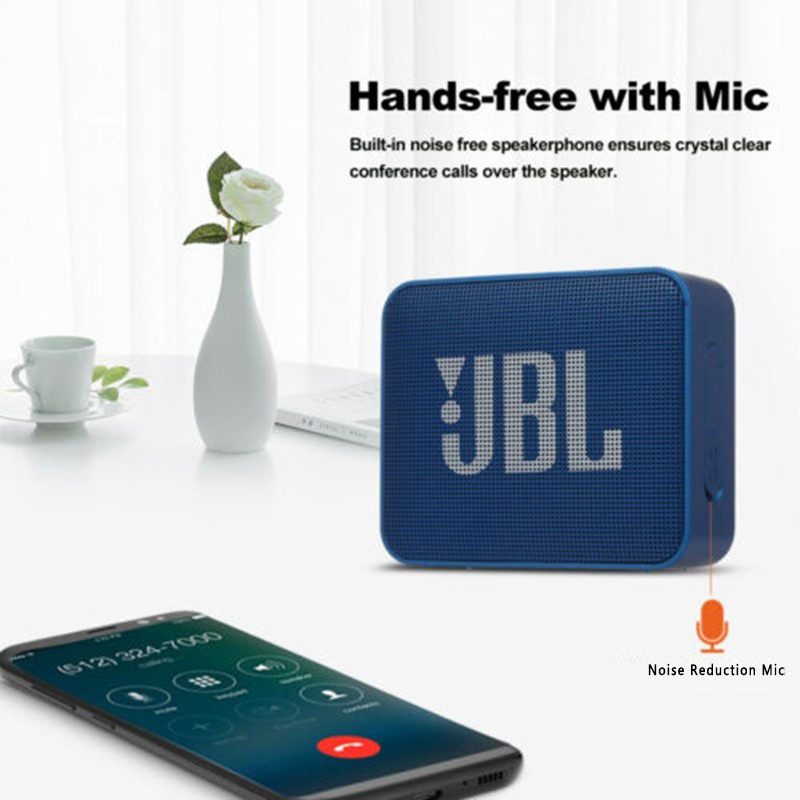 Blue JBL speaker with smartphone on a white surface with a vase and cup in the background