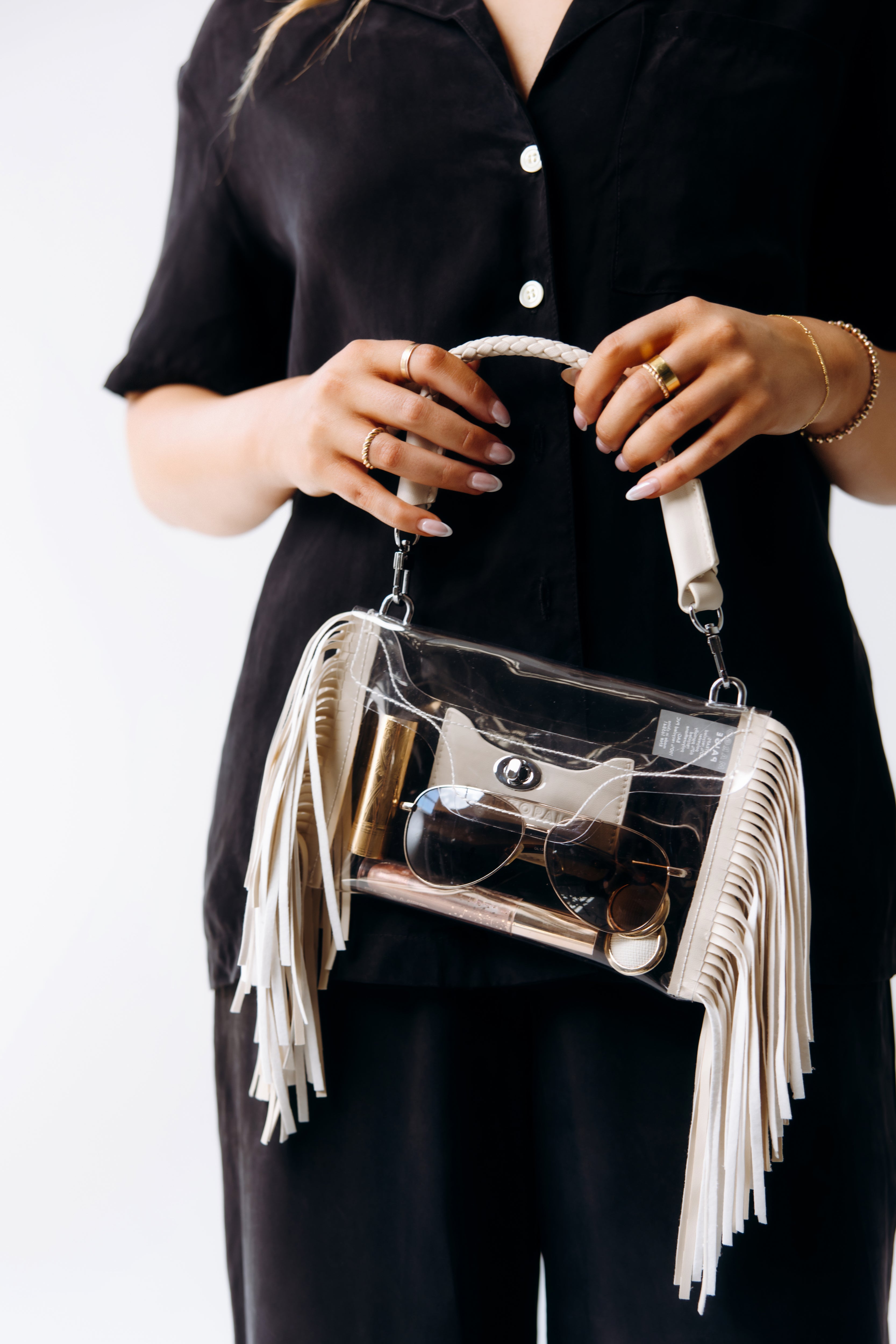 Person holding a clear fringe crossbody bag, showing its size and stylish design for easy use at events with clear bag policies.