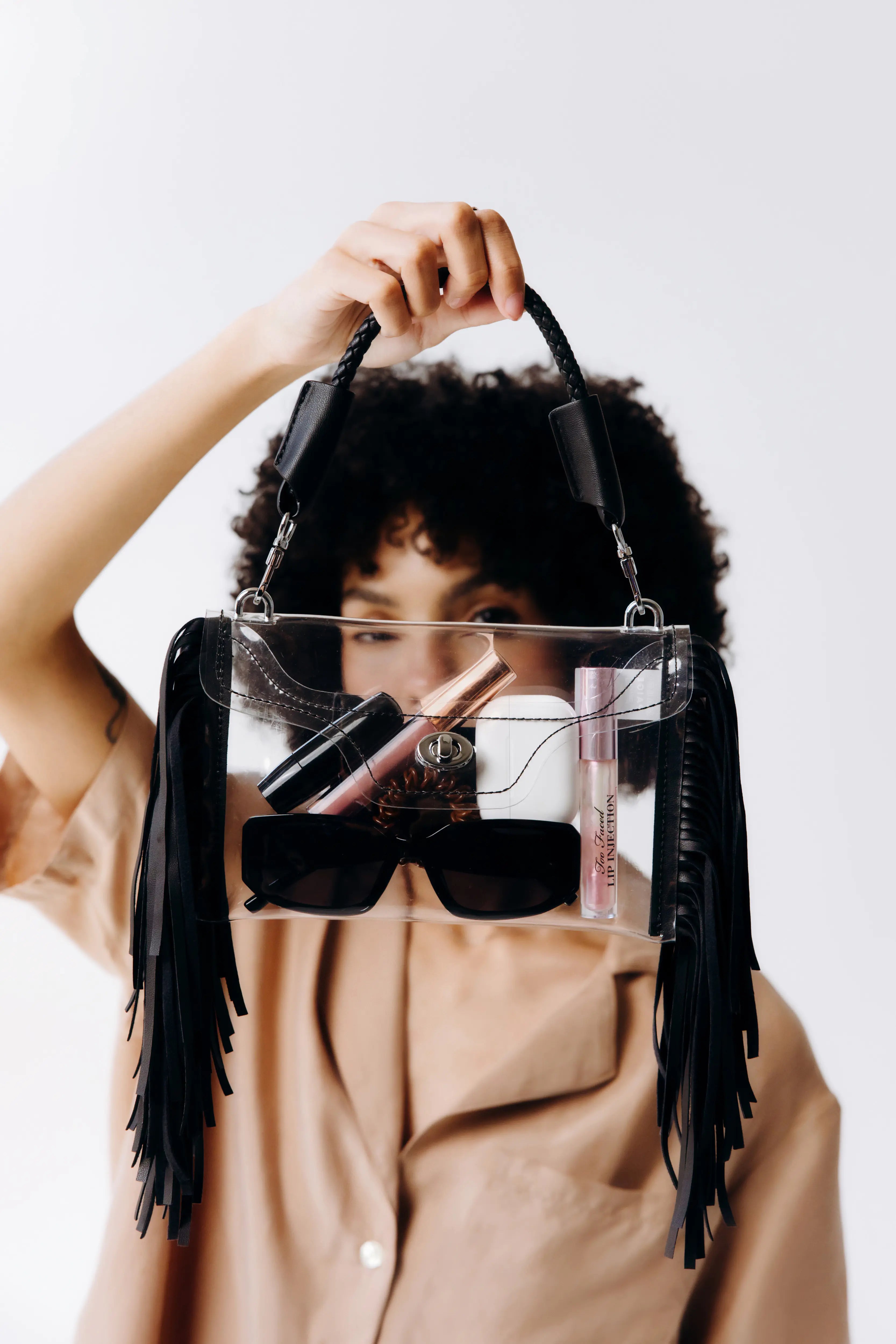 Person holding a clear fringe crossbody bag, showing its size and stylish design for easy use at events with clear bag policies.