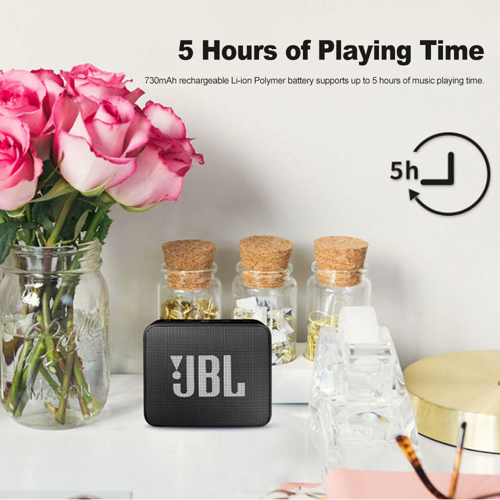 JBL speaker with pink roses and decorative jars on a white surface