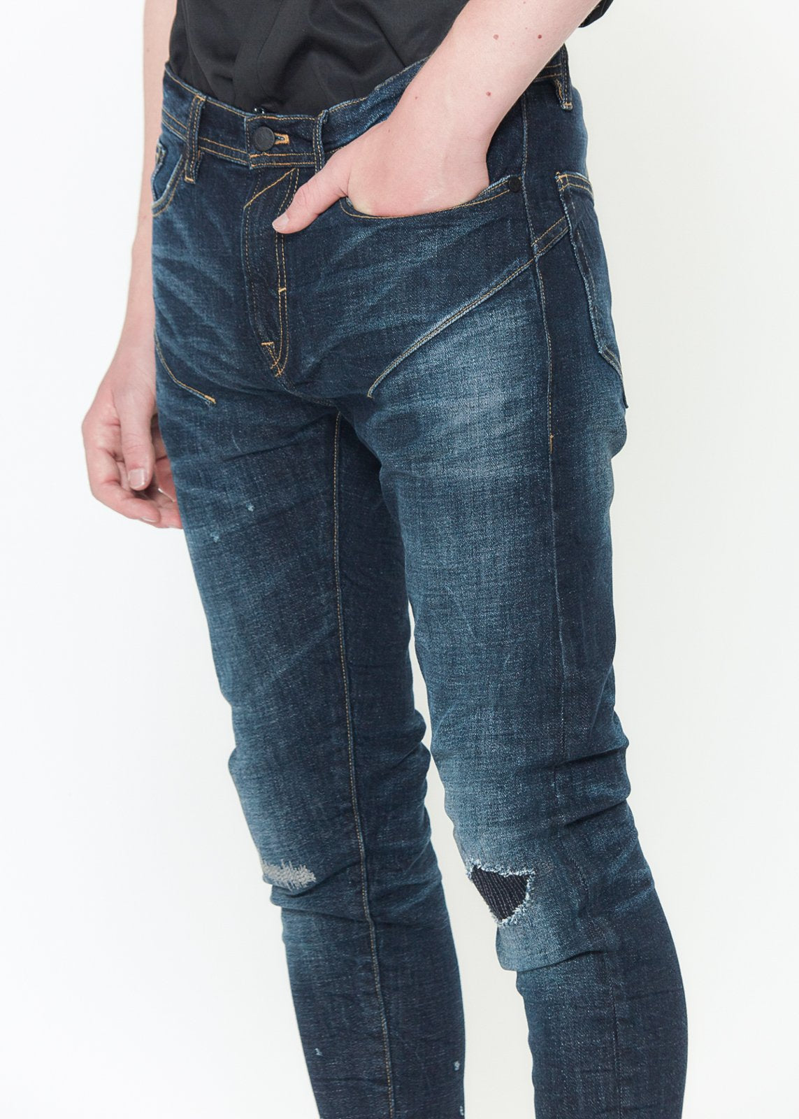 Close-up of the rip and repair patchwork and hand sanding on Konus distressed skinny jeans.