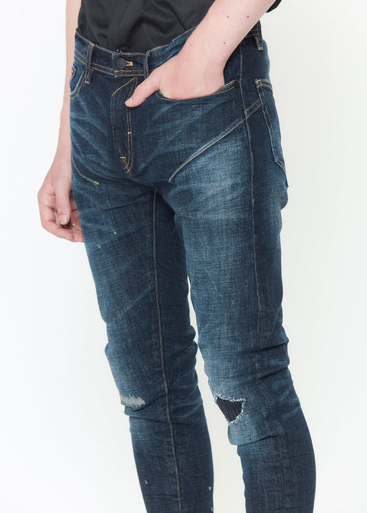 Close-up of the rip and repair patchwork and hand sanding on Konus distressed skinny jeans.
