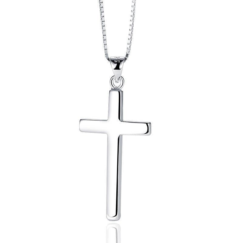 A polished silver cross pendant necklace on a matching silver box chain, shown against a plain white background with a subtle reflection below.