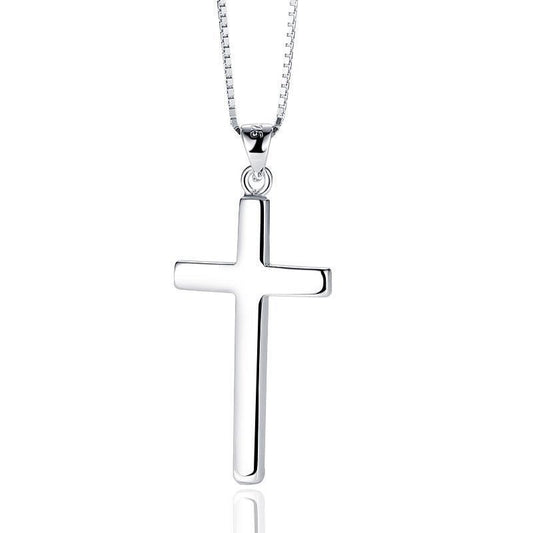 A polished silver cross pendant necklace on a matching silver box chain, shown against a plain white background with a subtle reflection below.