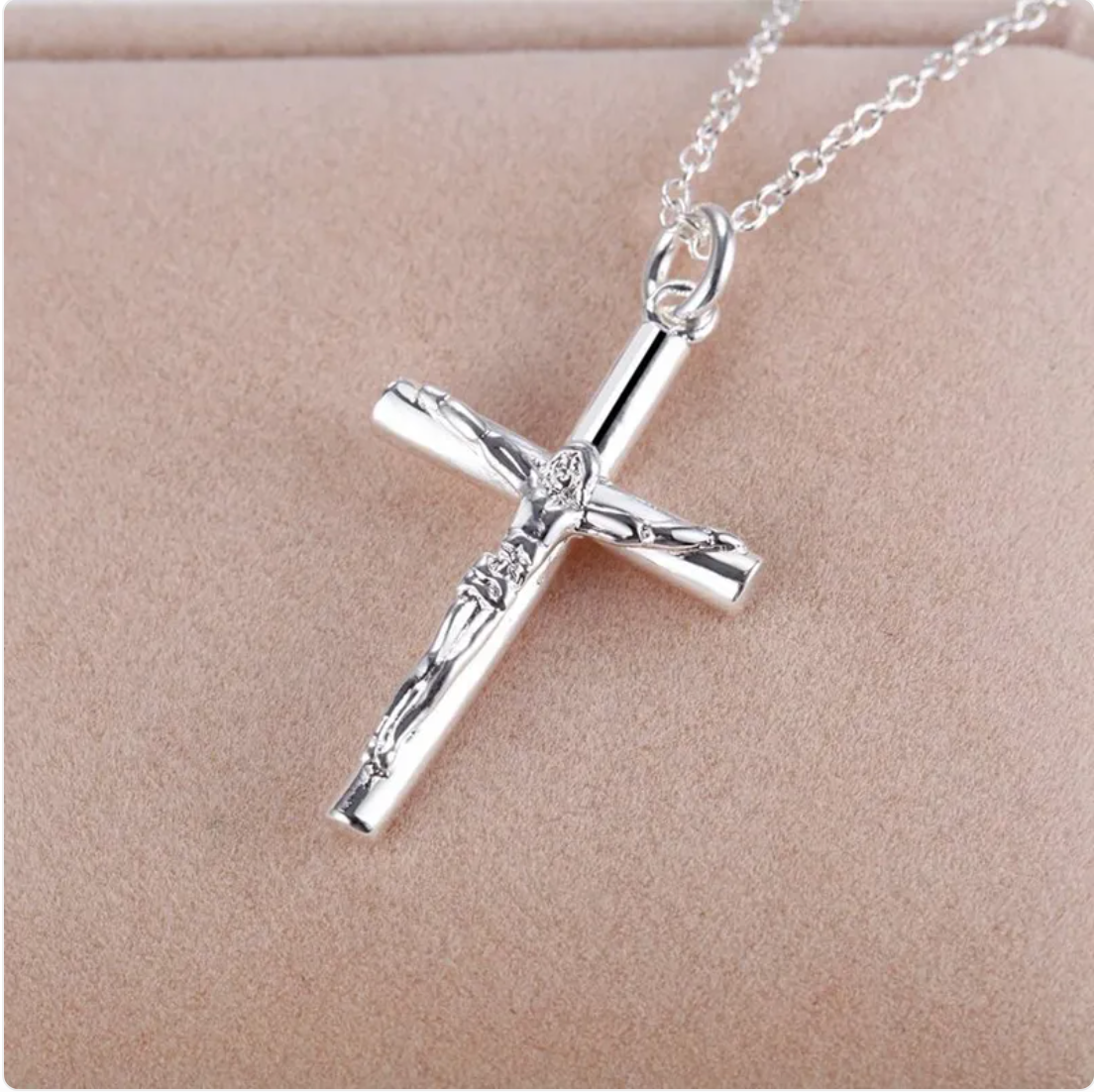 Silver cross necklace with a detailed design on a beige background.