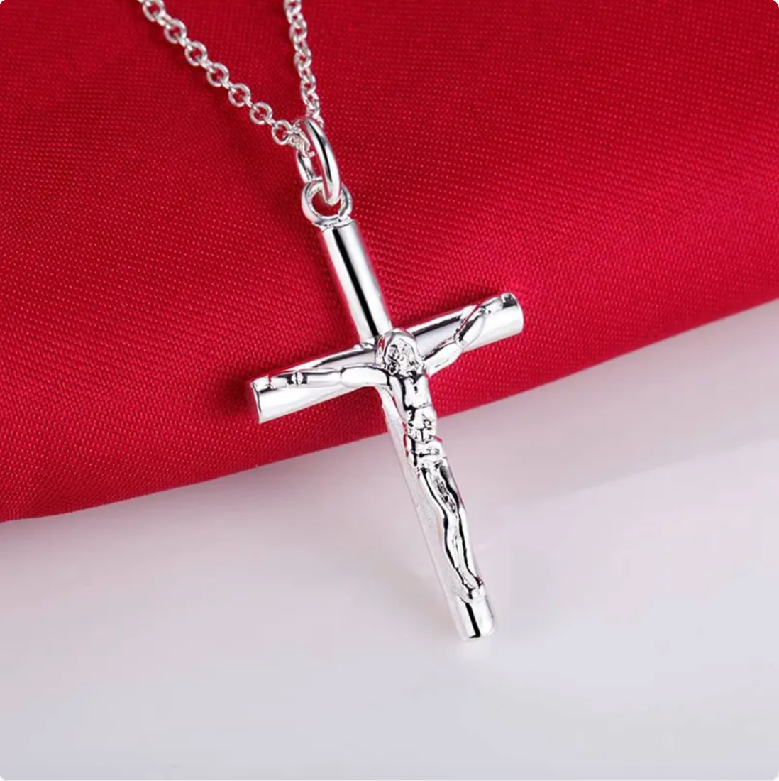 Silver cross pendant necklace on a red fabric background