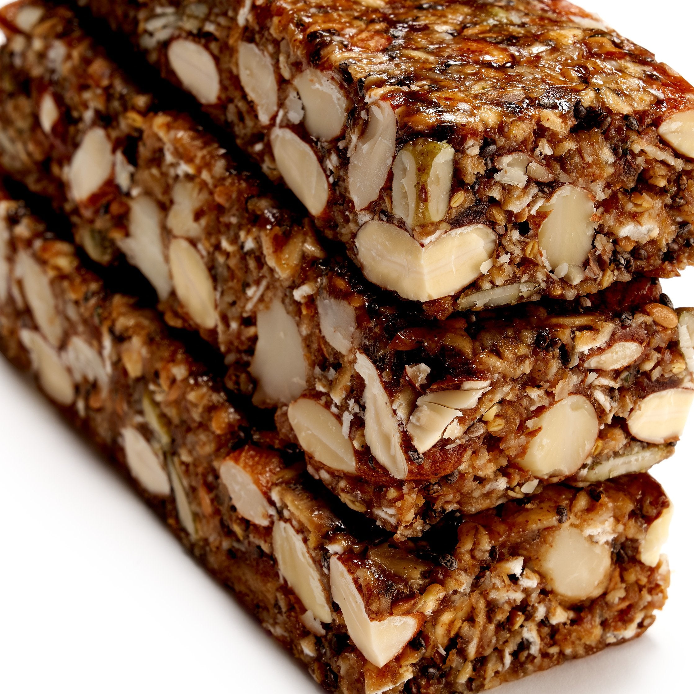 Trio of ivan.bars, with two partially unwrapped, illustrating the dense texture and visible legumes (nuts and seeds) on the surface.