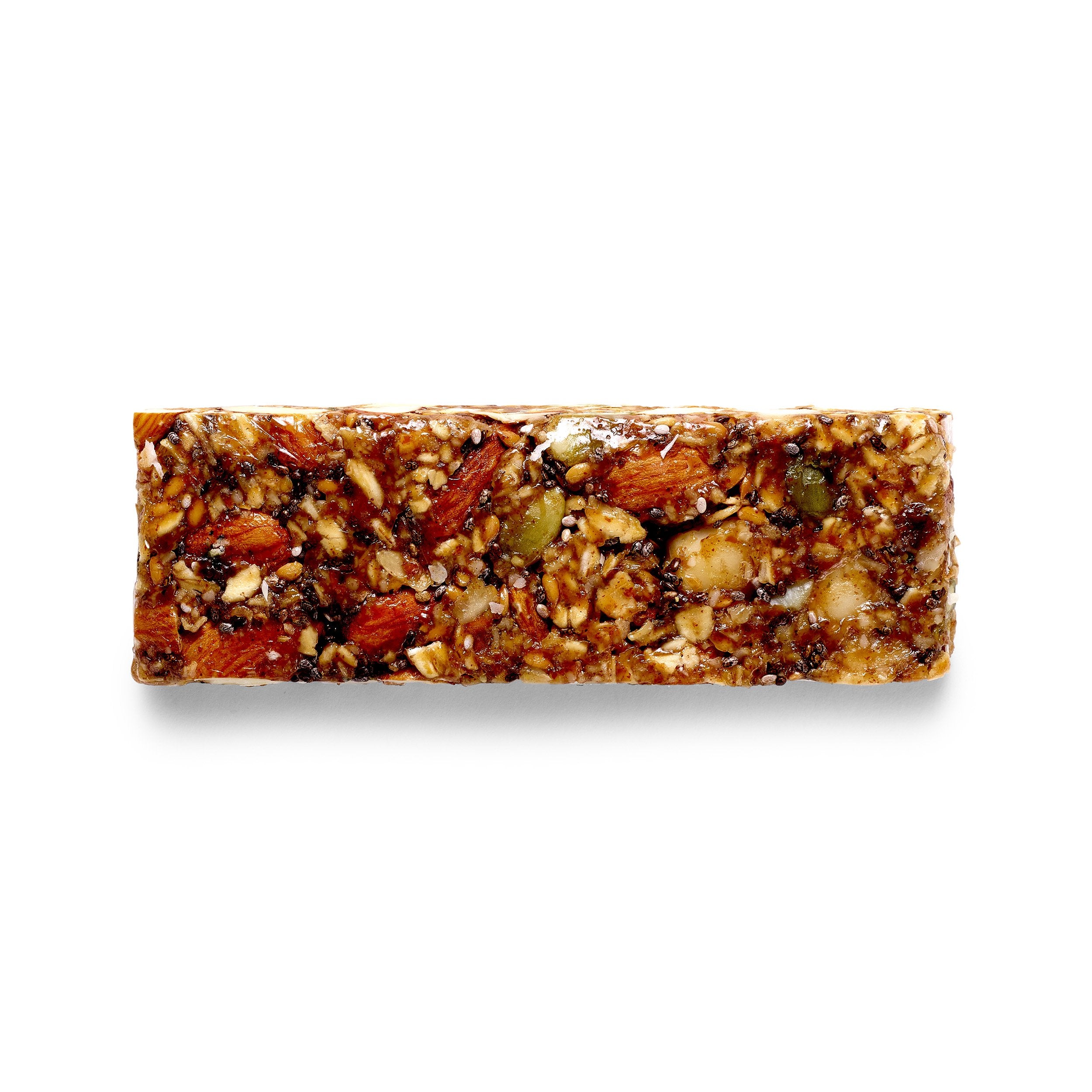 An ivan.bar resting outside its wrapper, slightly cracked to show the sticky, chewy interior texture and the abundance of whole ingredients.